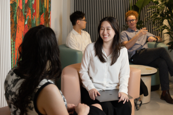 Students in professional dress having a discussion in an office space.