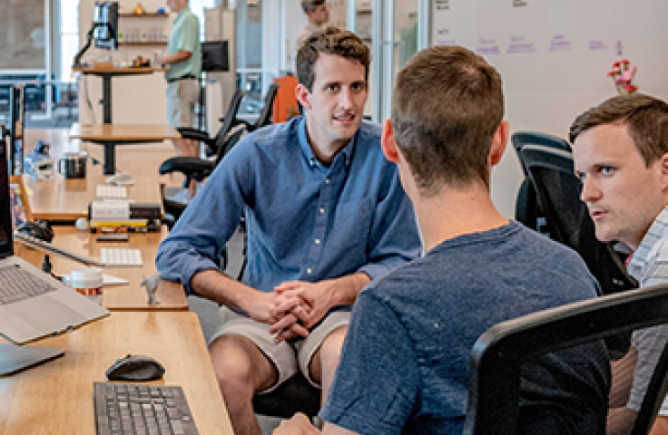 three men chatting round computer